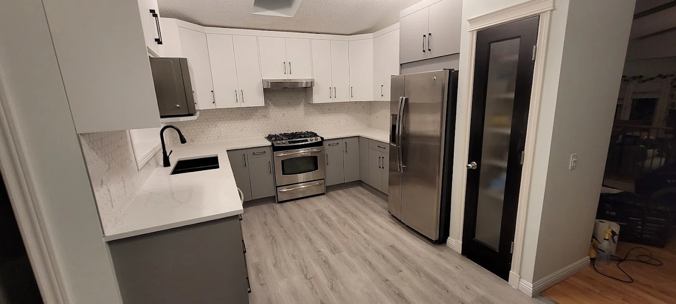 Completed Calgary-area kitchen renovation with white cabinets, counters and stainless steel appliances.